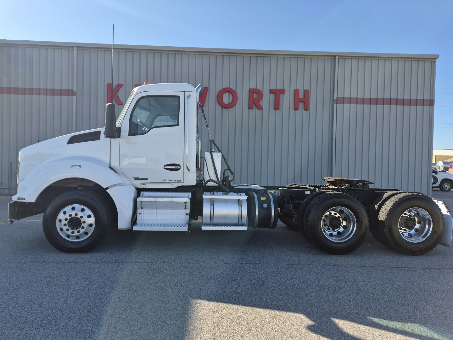 Kenworth T880 2018 conventional daycab tractor in white, side view with dual rear axles, fuel tanks, and wheel configuration visible.