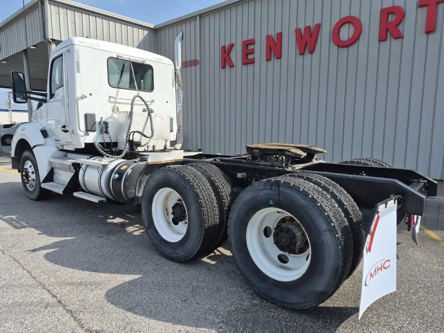 Kenworth T880 tractor cab with white exterior, dual rear axles, front cab view, near Kenworth sign.