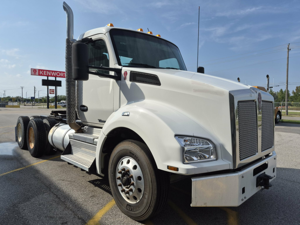 Kenworth T880 conventional daycab truck side view showing front grille, large exhaust stack, dual rear axles, and white paint.