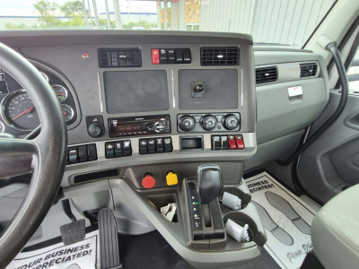 Kenworth T880 cab interior dashboard and gear shifter with steering wheel visible, center console controls, and multiple switches.