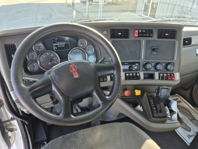 Kenworth T880 truck interior cockpit with steering wheel, dashboard gauges, control switches, and gear shifter.