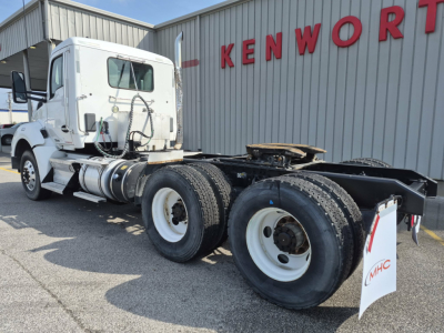 Kenworth T880 tractor cab with white exterior, dual rear axles, front cab view, near Kenworth sign.