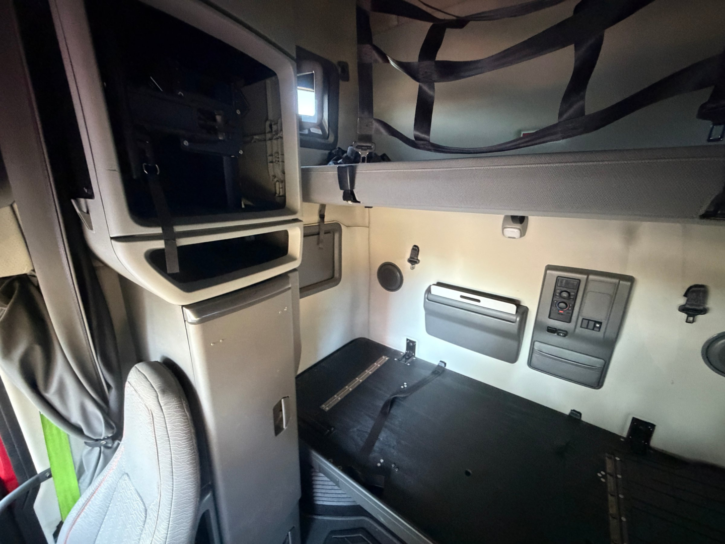 Cab interior of a Volvo VNL64T760 truck showing sleeper area with control panel, storage compartments, and overhead bunk area.