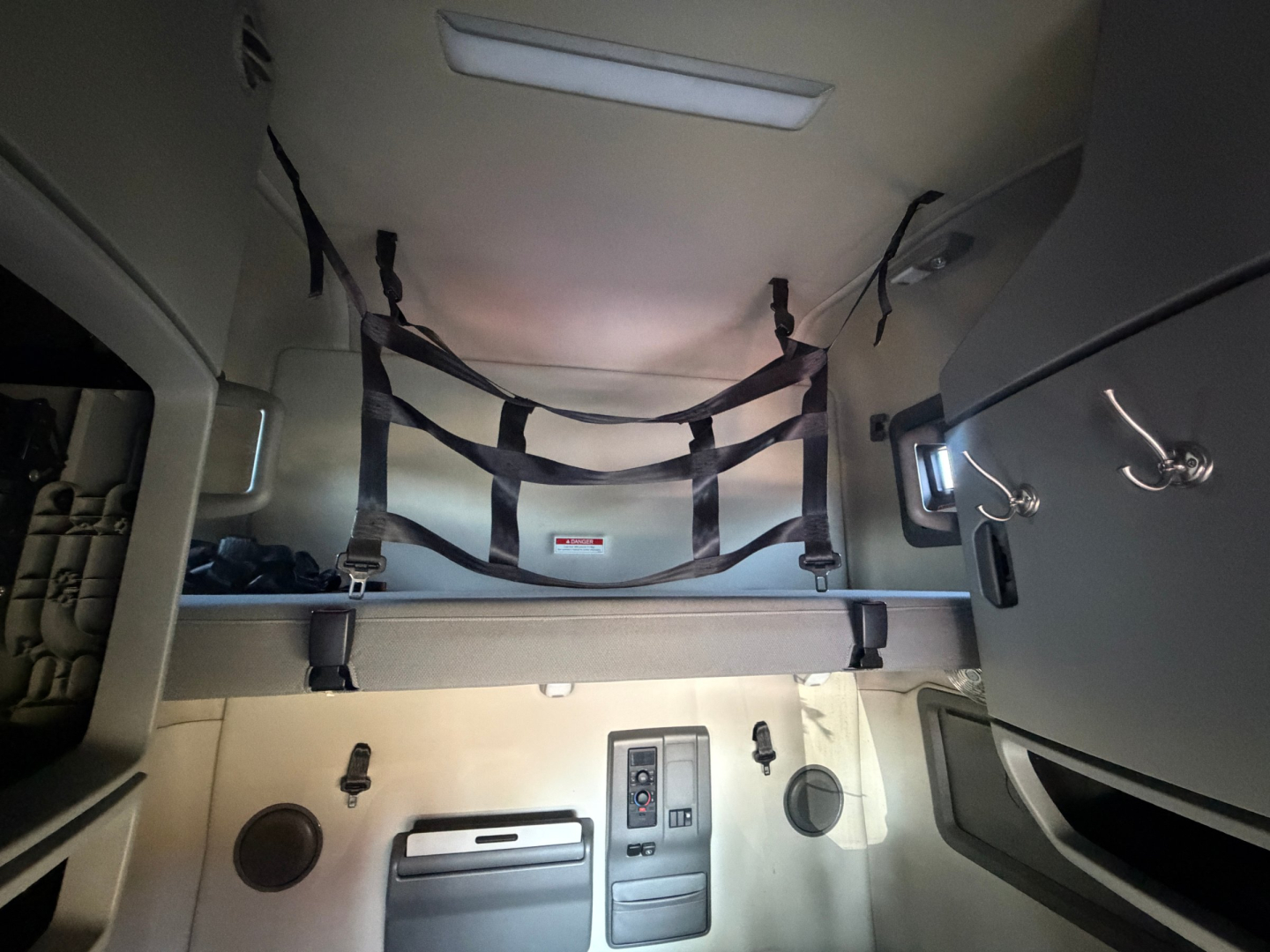 Volvo VNL64T760 cab interior showing overhead sleeping rack with straps and storage compartments.