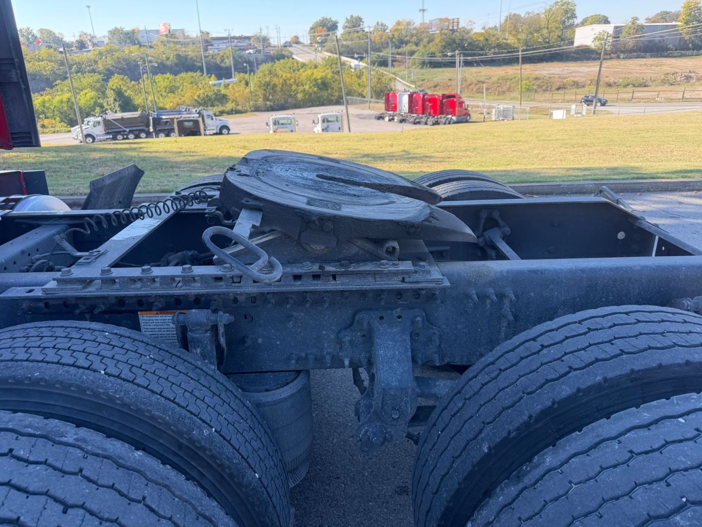 Truck chassis and fifth wheel/hub area showing dual rear axles with a circular component and linkage; no legible brand text visible.