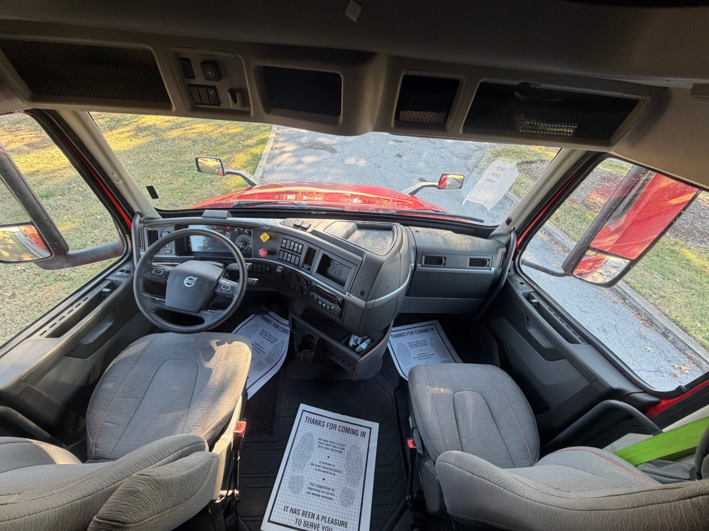 Volvo VNL64T760 truck cockpit interior view from driver’s seat showing dashboard, steering wheel, and front seats.