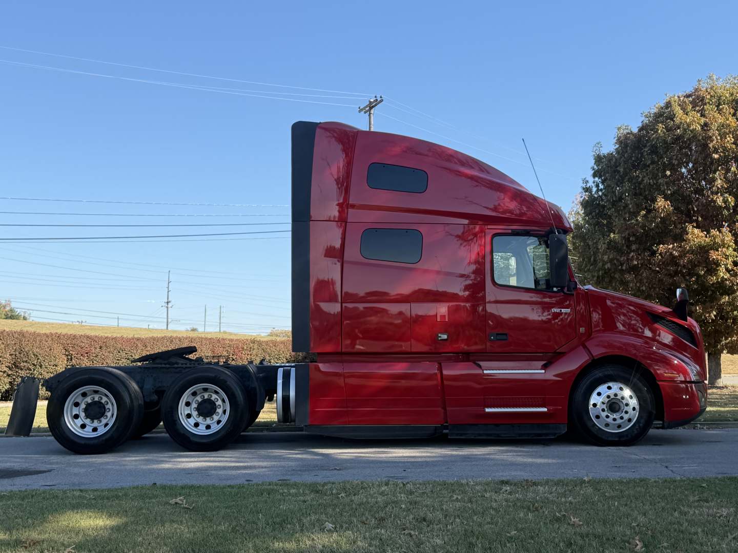 Side view of a red 2022 Volvo VNL64T760 sleeper cab tractor with a 6x4 axle configuration, showing rear wheels and side windows