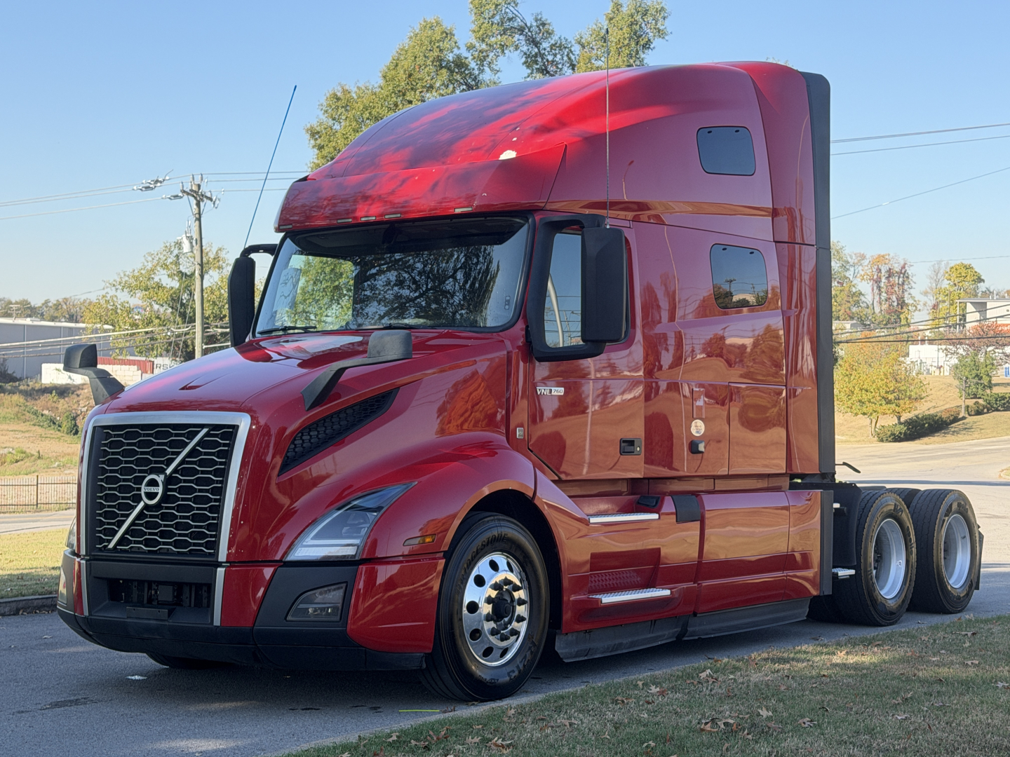 Volvo VNL64T760 truck in red color with sleeper cab, front grille, large side mirrors, and dual rear axles.