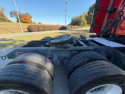 Dual rear tractor axles with dual rear tires and fifth wheel area of a Volvo VNL64T760 tractor-trailer showing exposed drivetrain and fuel tanks.
