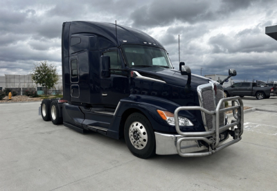 Kenworth T680 conventional sleeper truck in dark blue, front grille guard, chrome bumper, side mirrors, wheels, and dual rear axles visible.