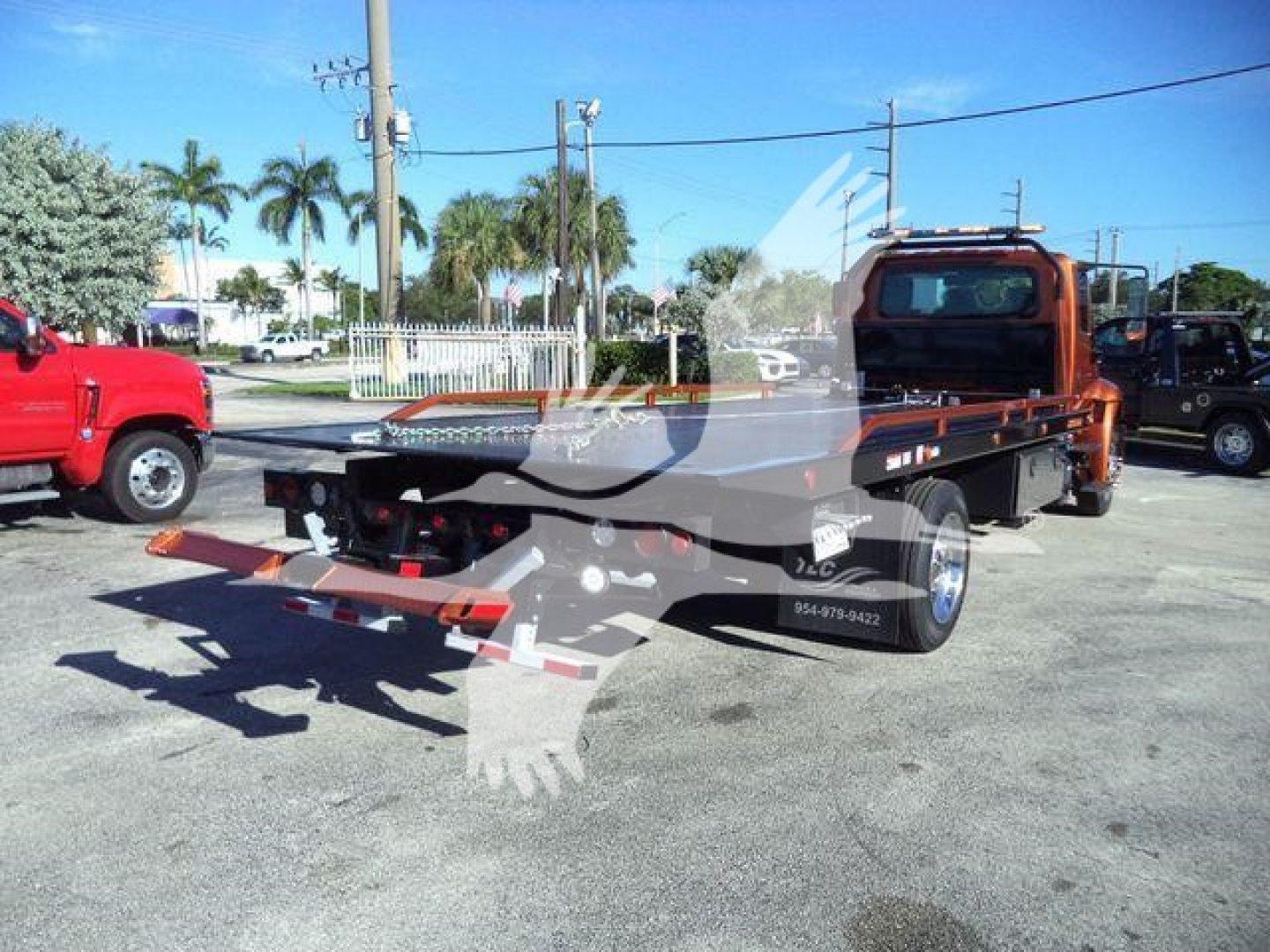 2019 International 4300 rollback truck with flatbed, orange cab, and equipment on lot. Stock number T20494FM shown in listing context.