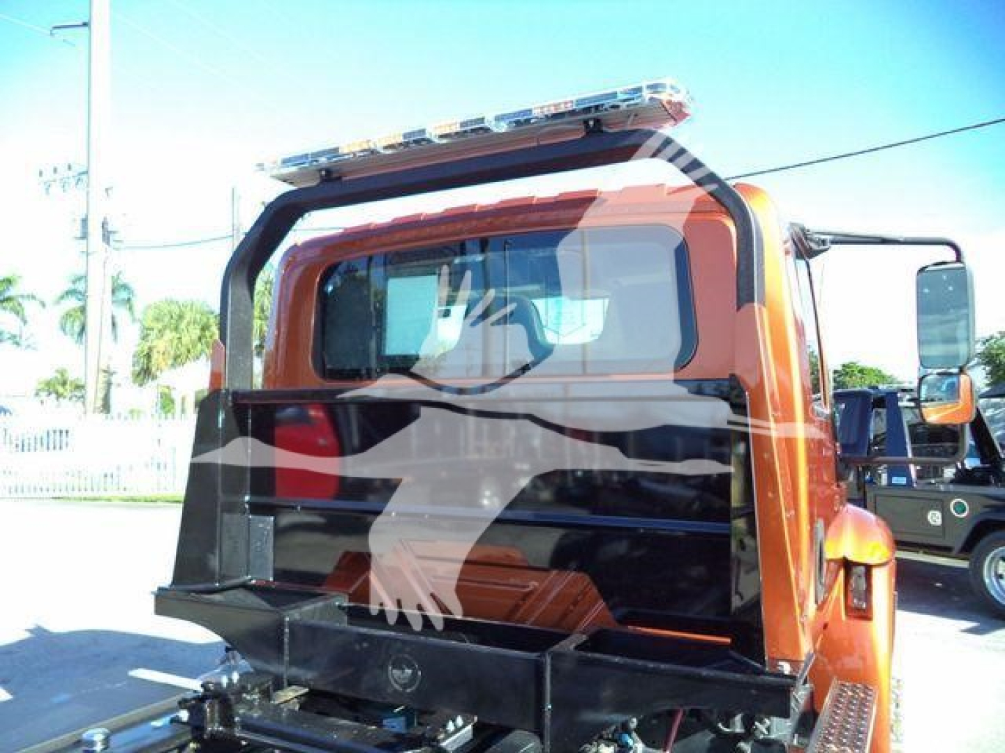 Truck cab rear view showing rollover rollback utility truck with orange cab and black spreader attachment