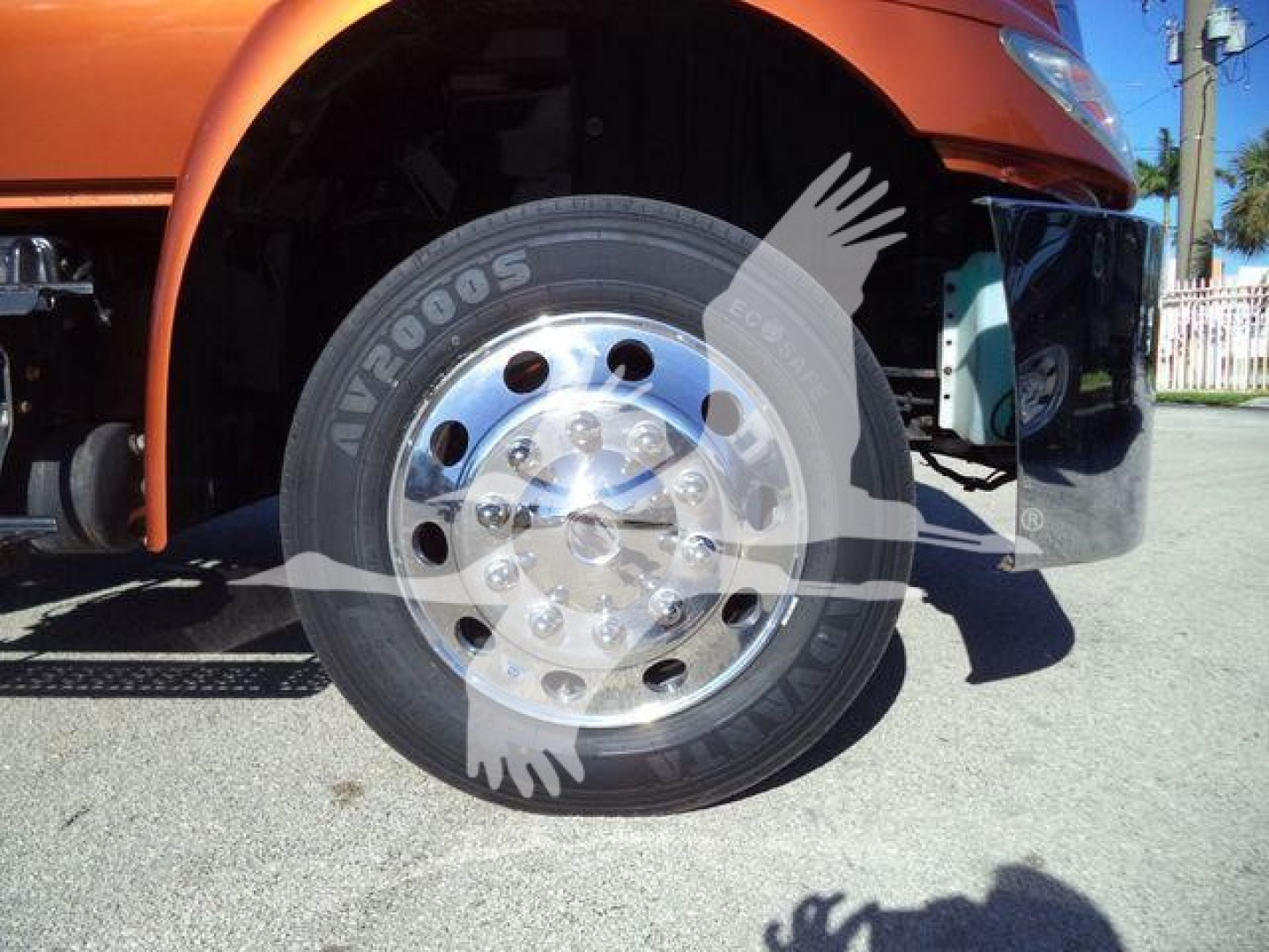 Wheel with tire and front fender of an orange 2019 International 4300 rollback truck showing tire and polished rim.