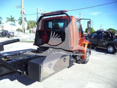 Truck chassis and cab of a 2019 International 4300 rollback truck showing rear toolbox and chassis frame.