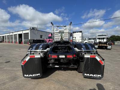 Rear view of a new 2027 Mack GR84FT conventional daycab showing dual rear wheels, black mud flaps with 'MACK' text, and chrome bumper with taillights.