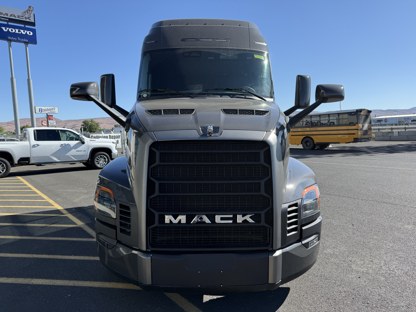 Front view of a 2026 Mack PR64T64M conventional sleeper truck showing large black grille with MACK badge, side mirrors, and cargo area cab.