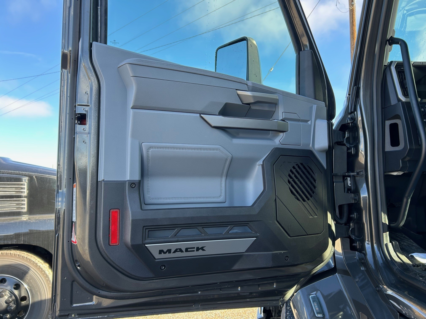 Mack truck door interior view showing panel, armrest, speaker grill, and 'MACK' logo on lower door edge.