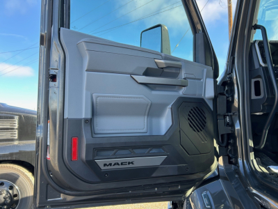 Mack truck door interior view showing panel, armrest, speaker grill, and 'MACK' logo on lower door edge.