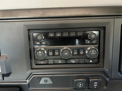 Truck dashboard with control panel, knobs, and buttons visible. No engine text readable in image.
