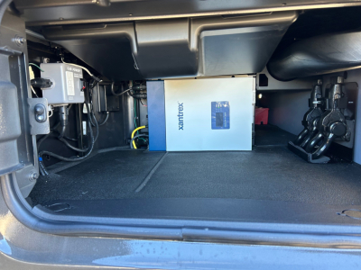 Undertruck storage compartment showing a blue-and-white Xantrex power inverter in a Mack PR64T64M sleeper truck.
