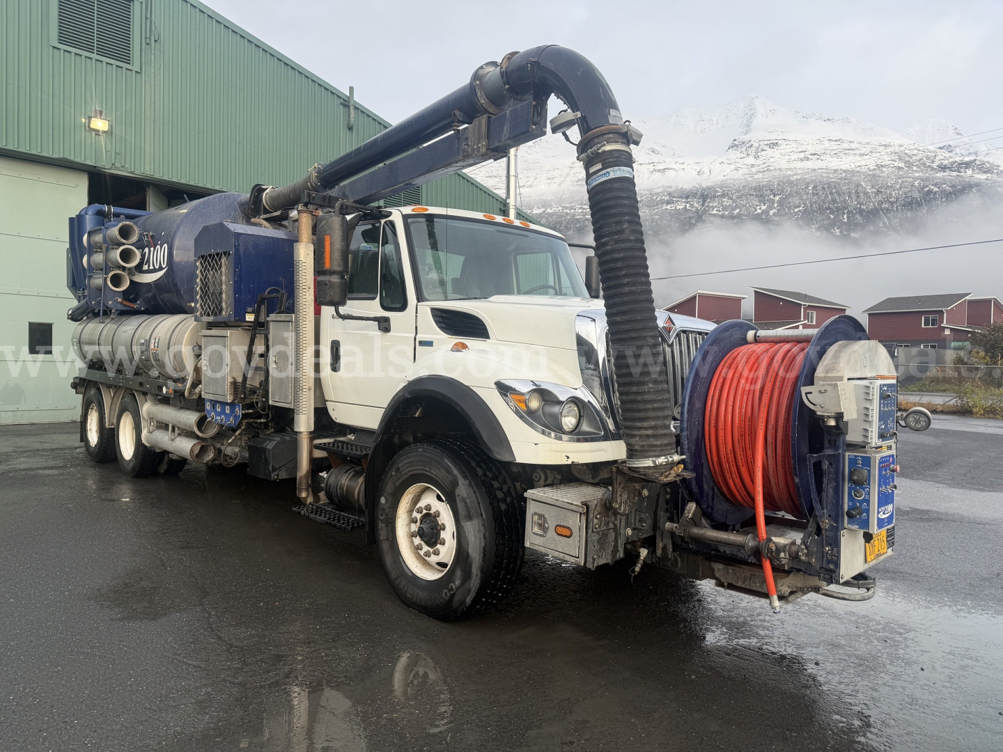 International WorkStar vacuum truck with large reel and hose, side view showing suction unit and hose reel.