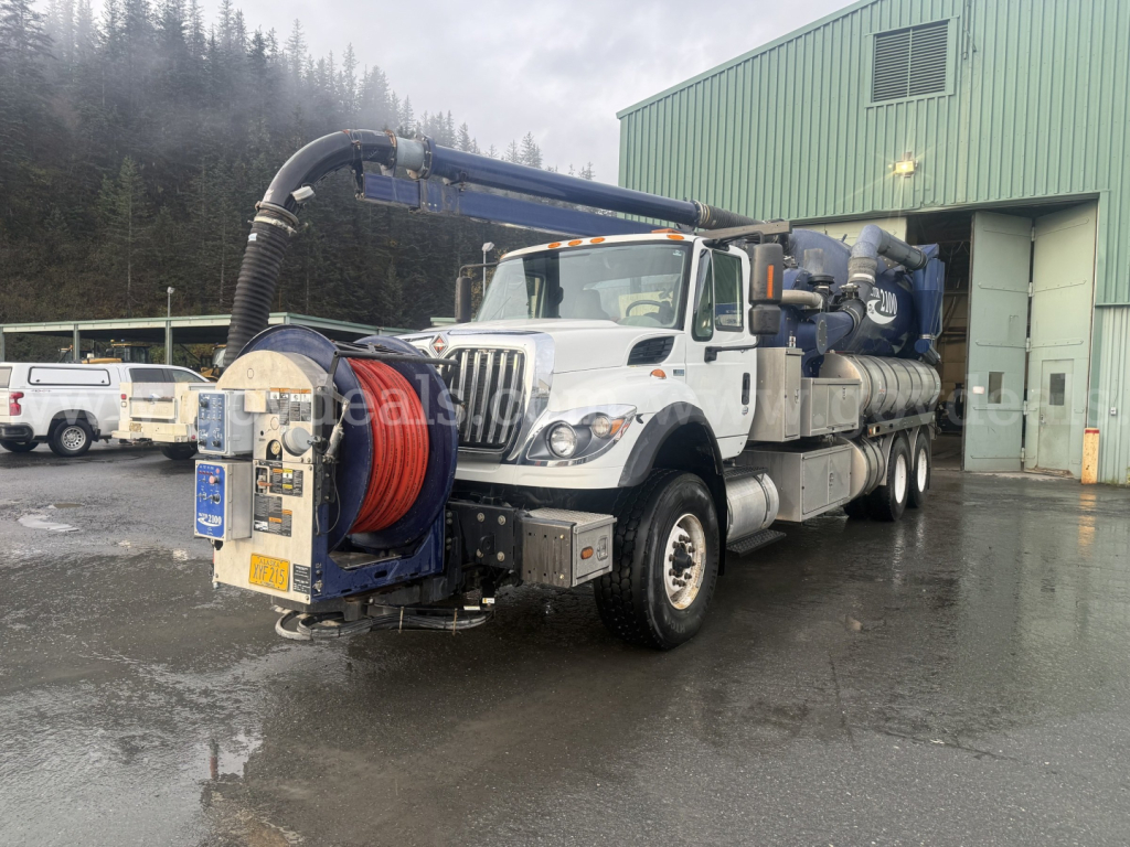International WorkStar 7500 vacuum truck with long hose reel and mounted water/pm equipment, white cab, blue articulated boom, in-service photo.