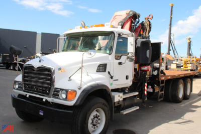 Mack CV713 truck with knuckle boom crane mounted on a flatbed, white cab, front view showing crane apparatus and supporting outriggers.