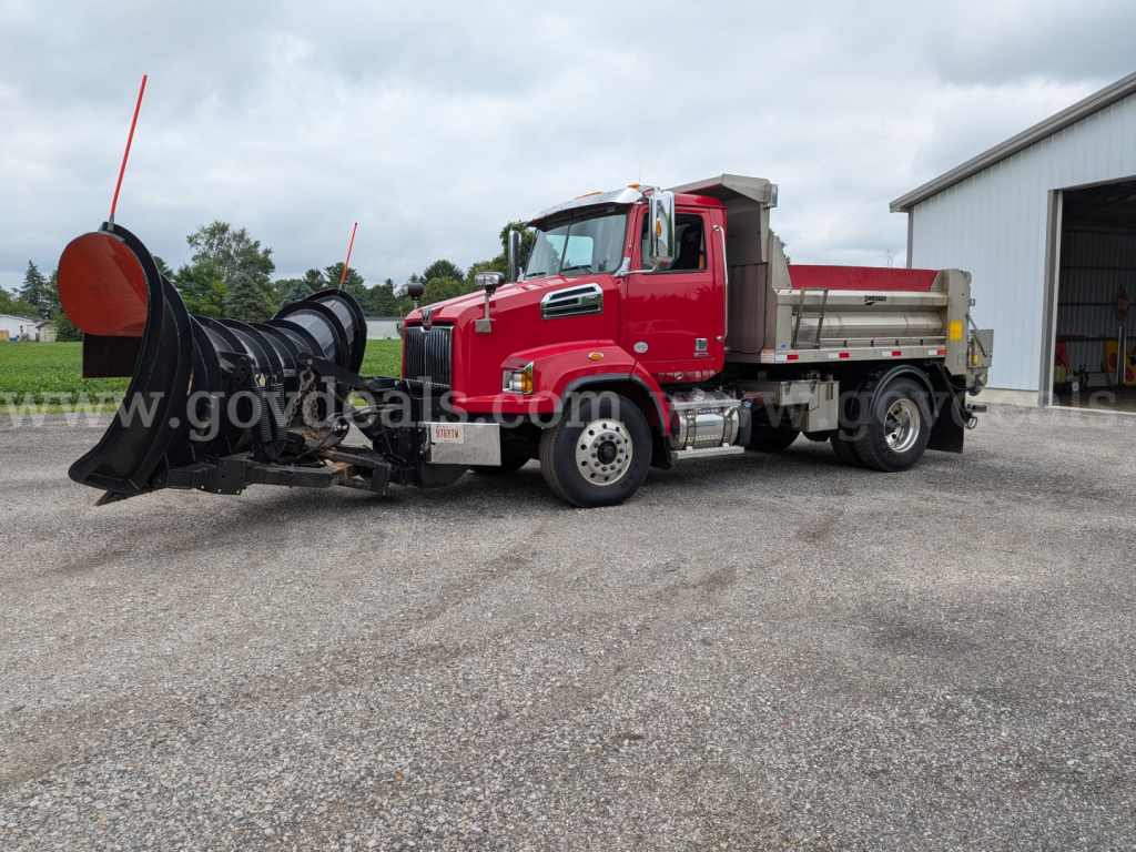 Heavy-duty diesel truck with plow attachment in front, red cab and dump bed, Western Star 4700 used for snow plowing.