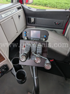 Interior of a Western Star 4700 cab showing plow controls panel with three levers and round handles, touchscreen display, cup holders, and dash label 'Western Star'.