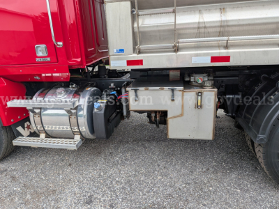 Side view of a red Western Star 4700 truck with a silver dump bed. Visible text includes partial VIN plate and stock number area, plus miscellaneous labels on the chassis and fuel tanks.