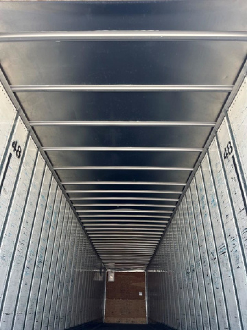 Trailer interior showing corrugated metal walls with side rails and numbers 456 on the doors, empty cargo area.