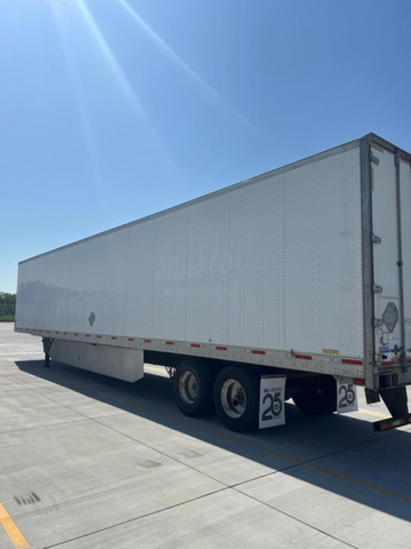 Trailer body and rear view showing white dry van with dual rear axles and cargo doors, exterior DOT reflectors visible, parked on pavement.