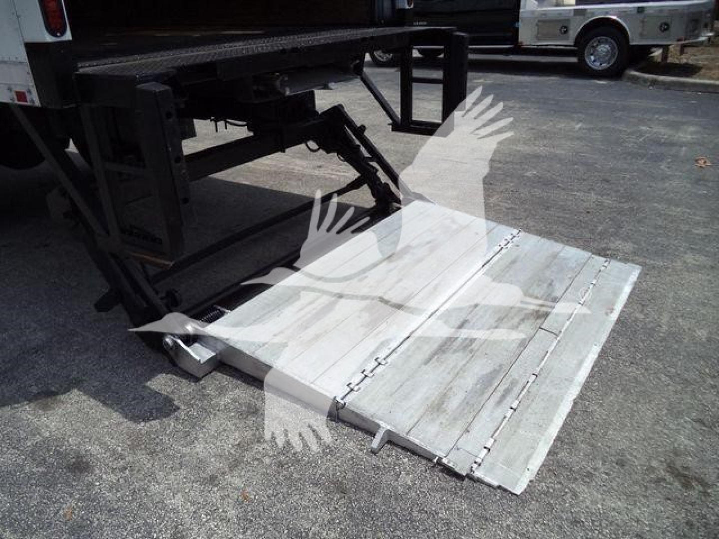 Truck rear with aluminum lane ramp/step extending from trailer, metal platform details visible.