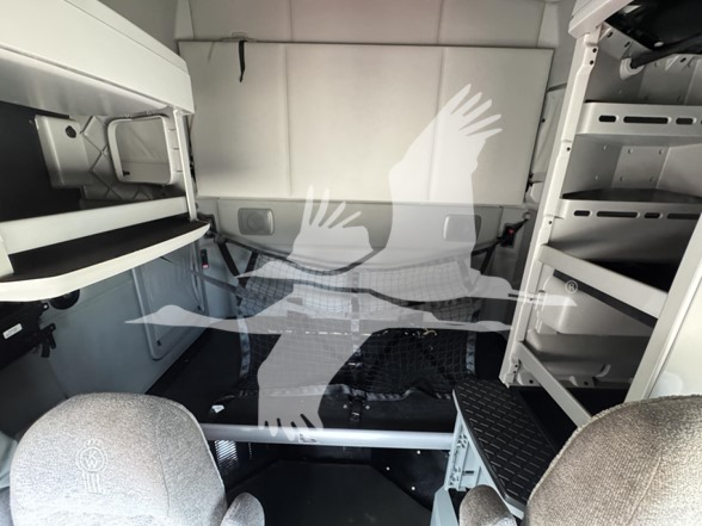 Kenworth T680 sleeper cab interior view showing cabin storage shelves, crew area, and floor with metal step rungs.