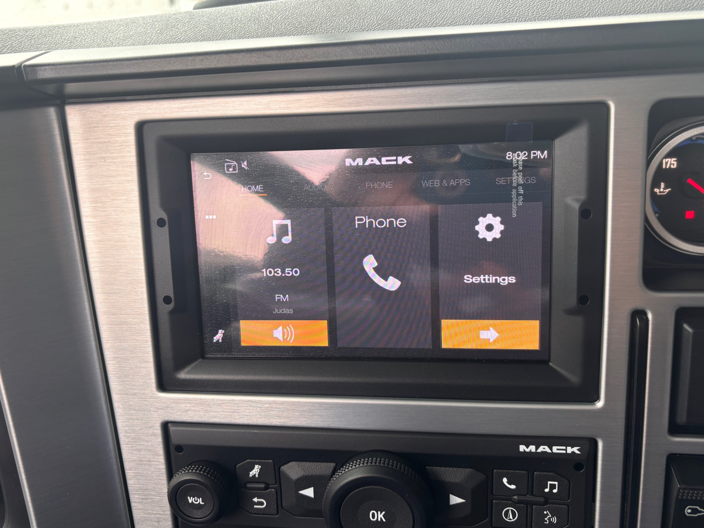 Mack PI64 dash area showing touchscreen infotainment with home screen icons and 'MACK' branding.