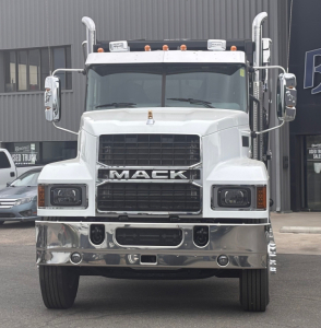 Mack PI64 dump truck front view showing large grille with MACK lettering, white cab, chrome bumper, dual side mirrors, and elevated exhaust stacks.
