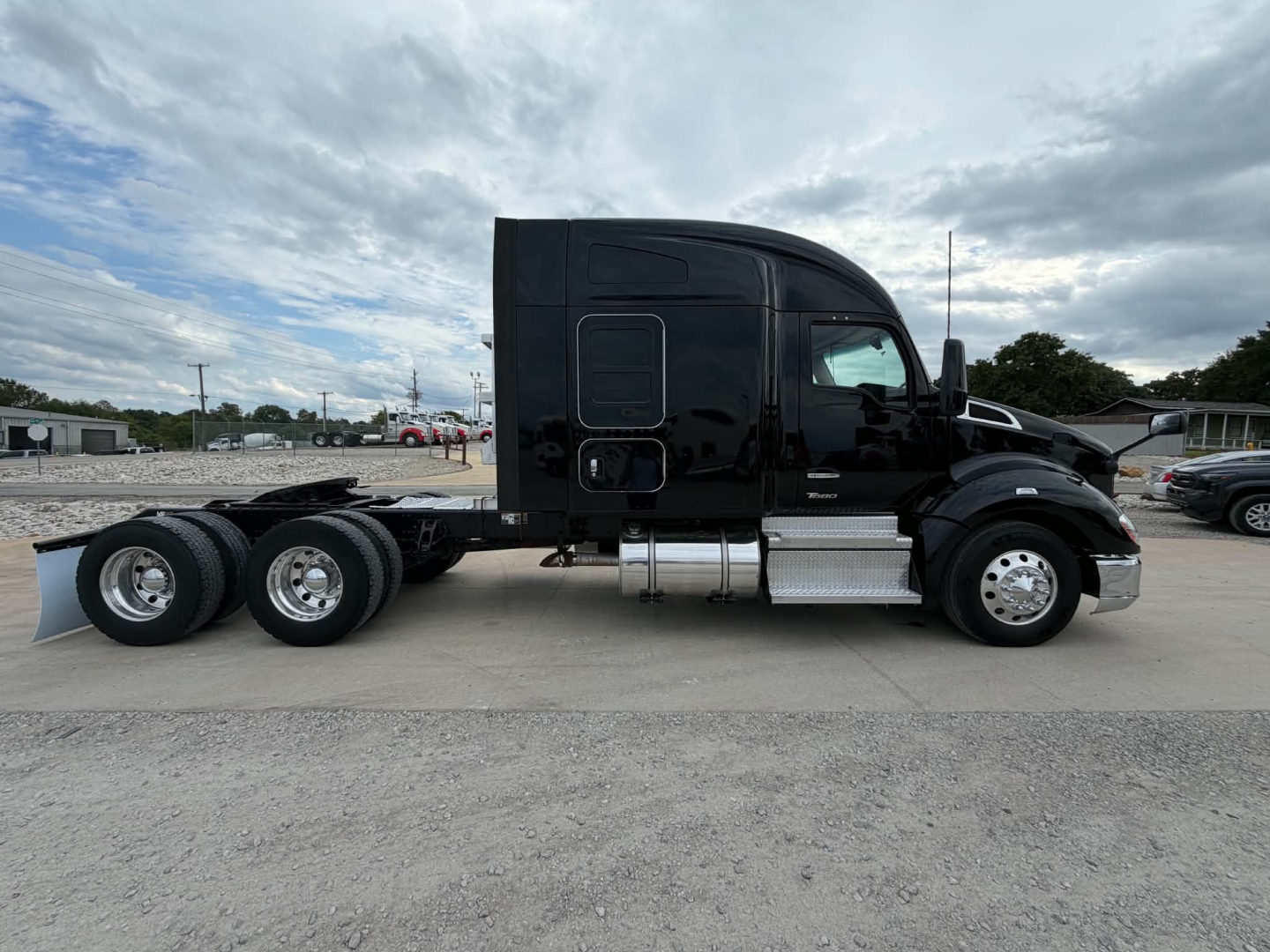 Kenworth T680 conventional sleeper truck side view showing dual rear axles and chrome fuel tanks, black paint, VIN plate area not visible.