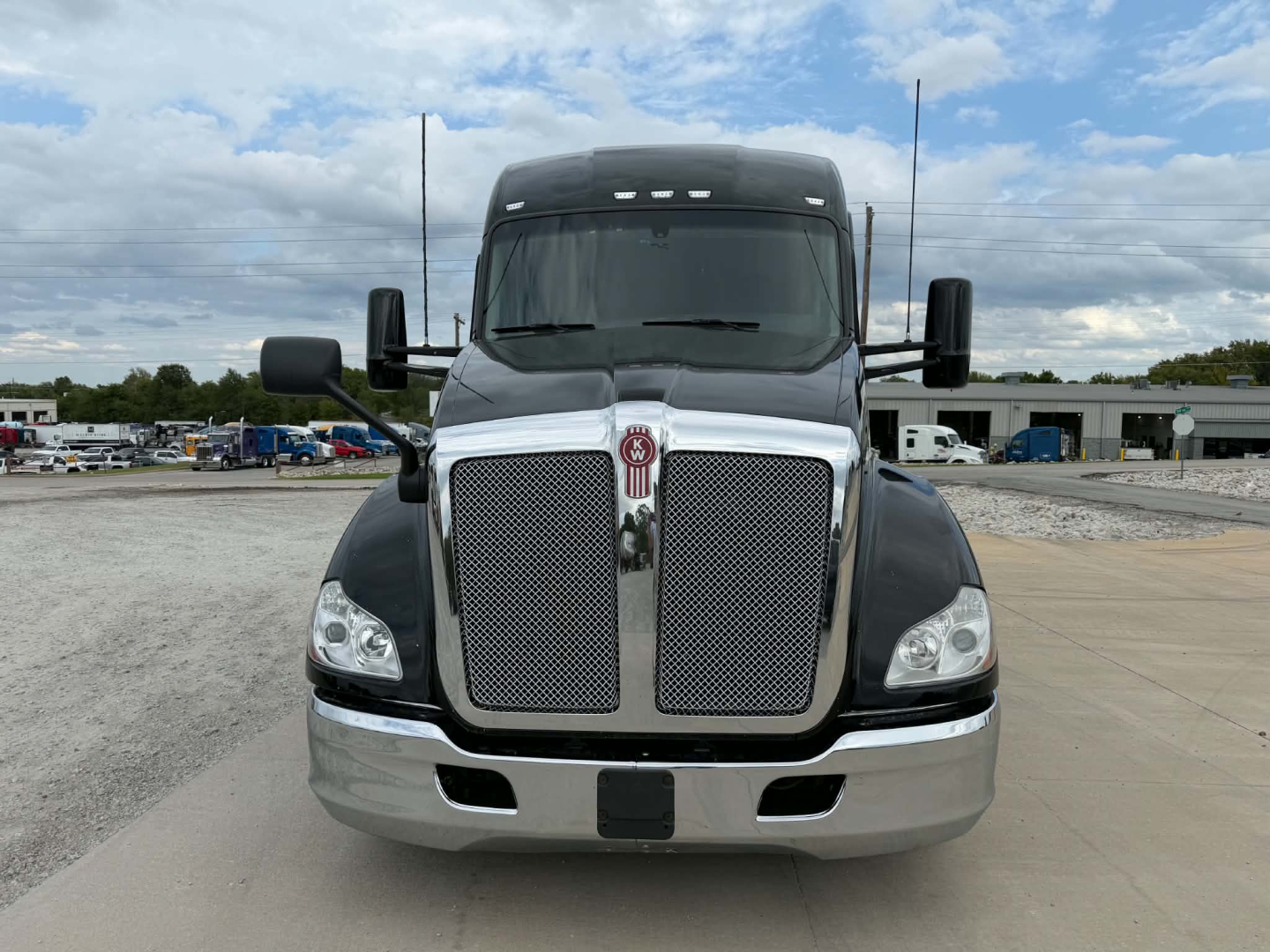 Kenworth T680 front view showing large chrome grille with Kenworth emblem, headlights, and bumper; clear windshield and side mirrors.