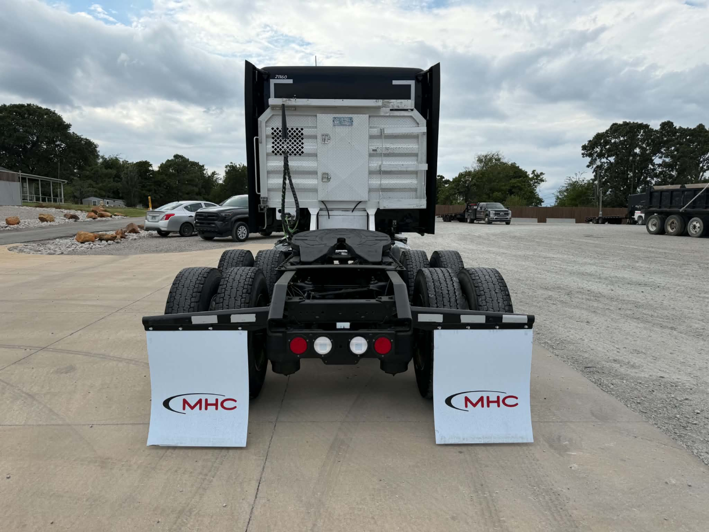 Kenworth T680 rear view showing dual rear axles, dump-style trailer hitch, mud flaps with MHC logo, and utility space behind cab.