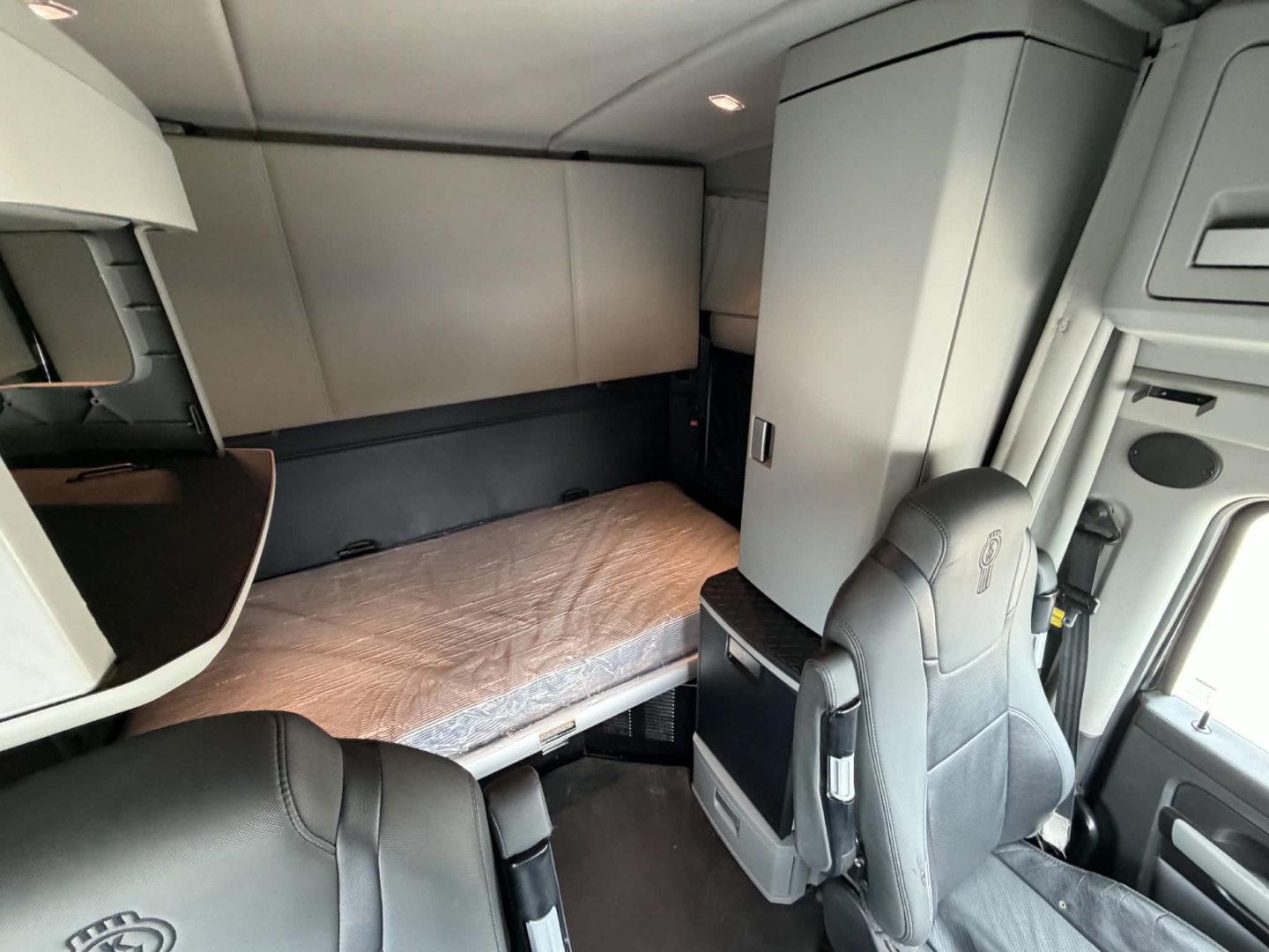 Kenworth T680 sleeper cab interior with bed, storage cabinets, and driver seat. Visible text includes VIN and stock details in listing context.