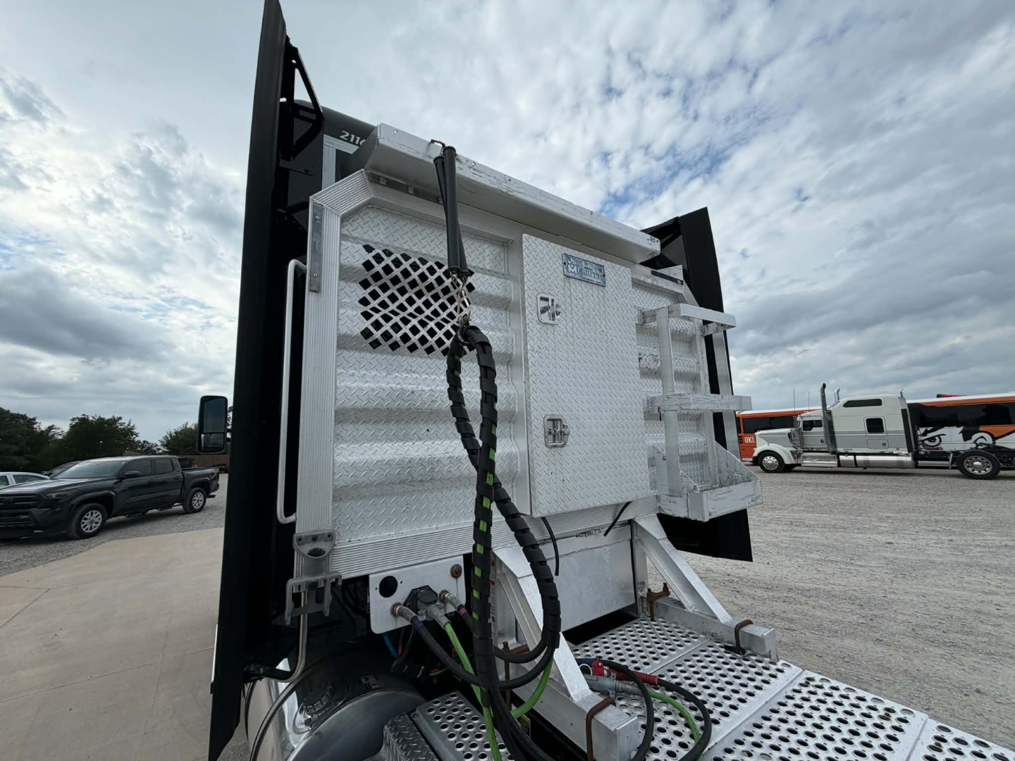 Kenworth truck dump bed with hydraulic lines and control panel; visible labels and hoses on a metallic surface.