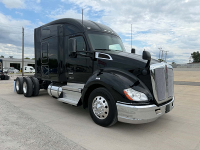Kenworth T680 sleeper cab tractor in black showing side with fuel tanks and chrome steps.