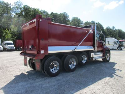 Dump truck with red cargo bed and dual rear wheels, Western Star 49X, side view showing dump bed and chrome exhaust stack.