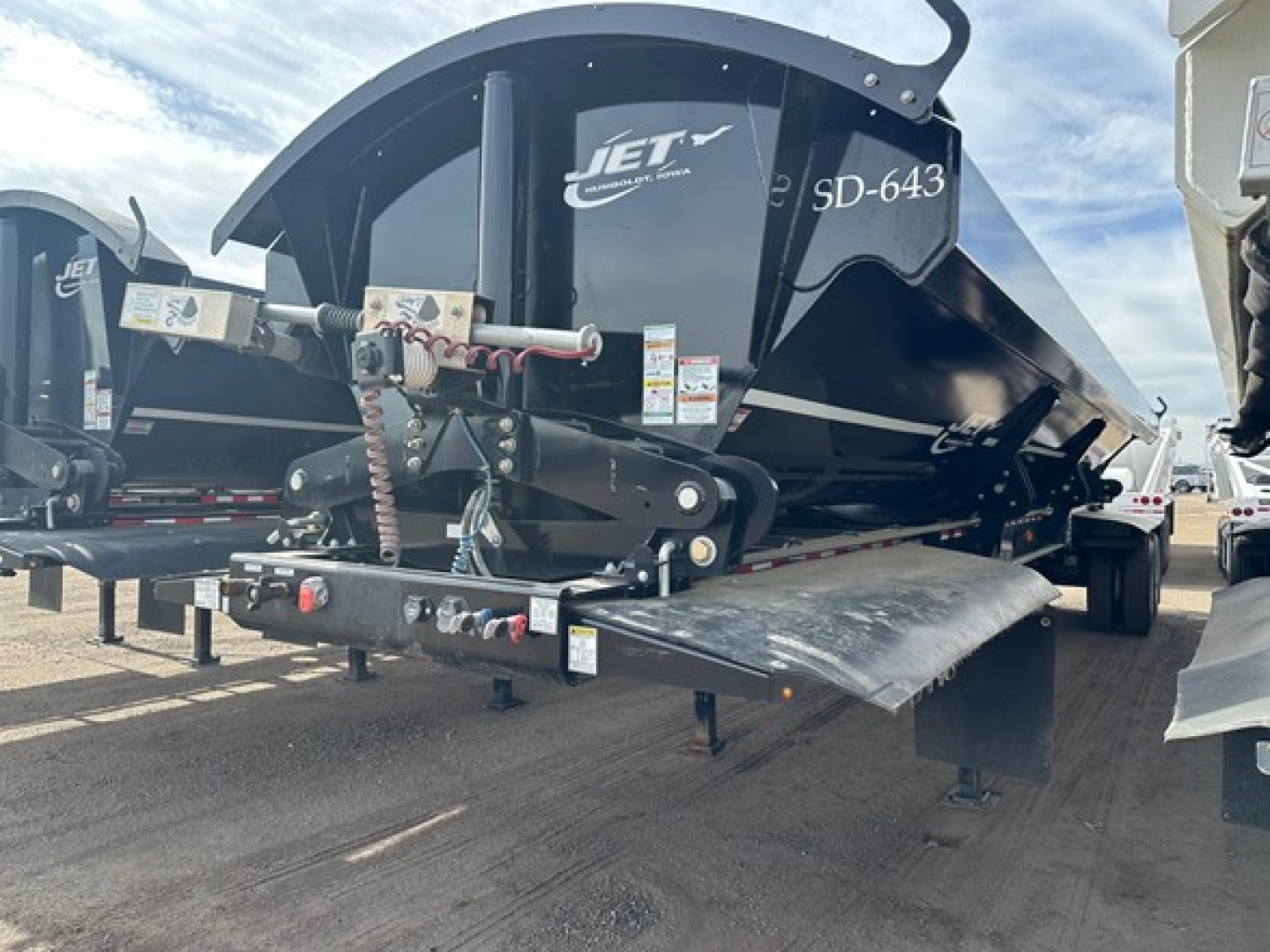 Jet SD-643 side dump trailer undercarriage with hydraulic cylinder and ramp, front hitch area visible, black paint and Jet branding.