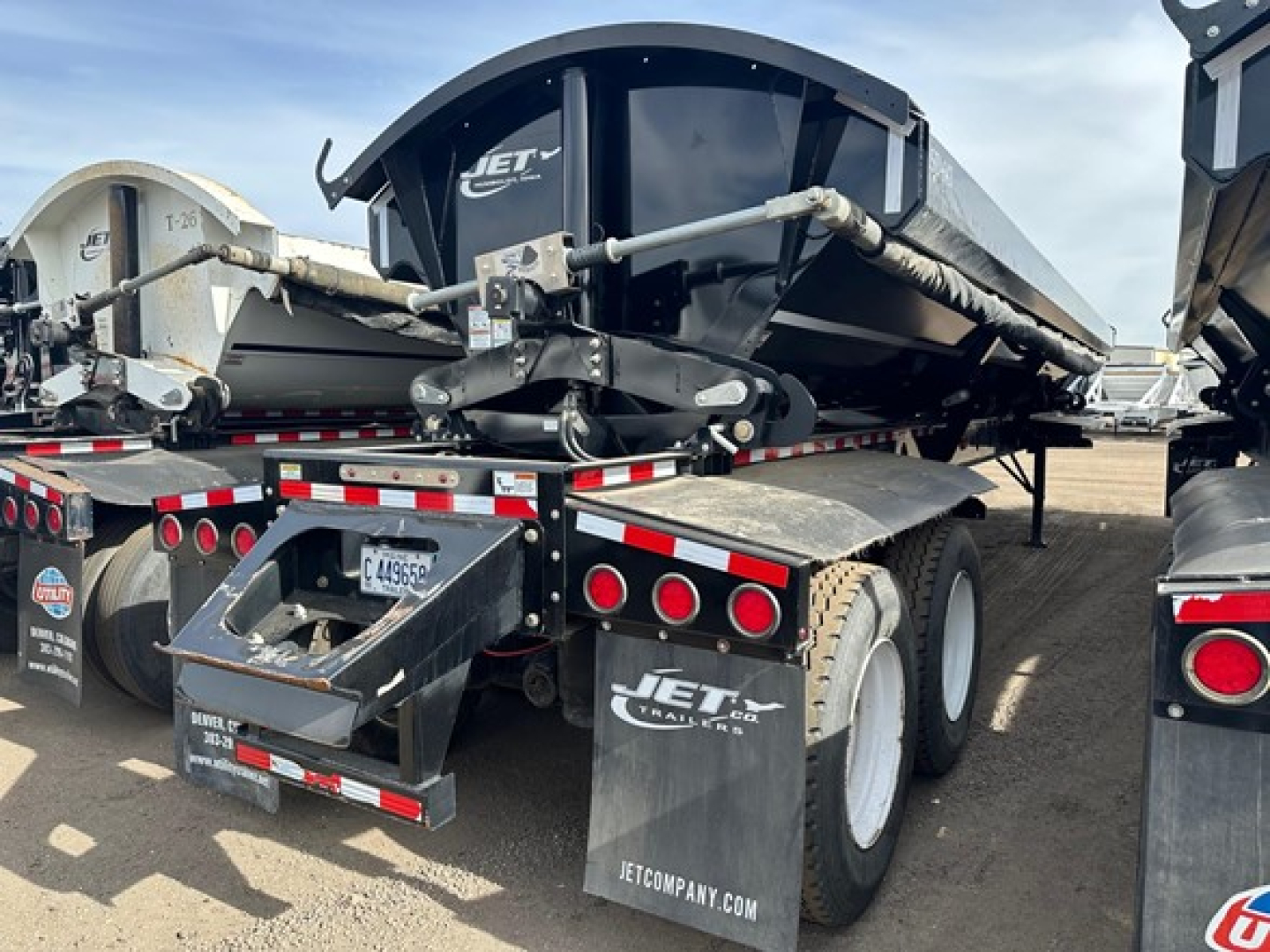 Jet Side Dump trailer showing rear view with black hopper and dual rear wheels, hydraulic tailgate, and Jet Co. branding on mudflaps.