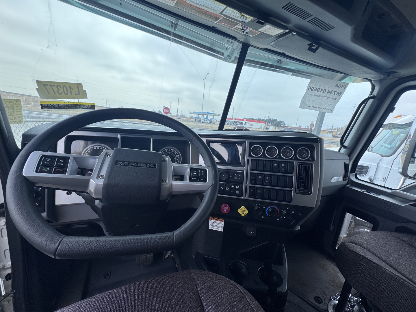Truck cab interior of a 2026 Mack PI64 showing steering wheel, dashboard with gauges, radio, and control switches.