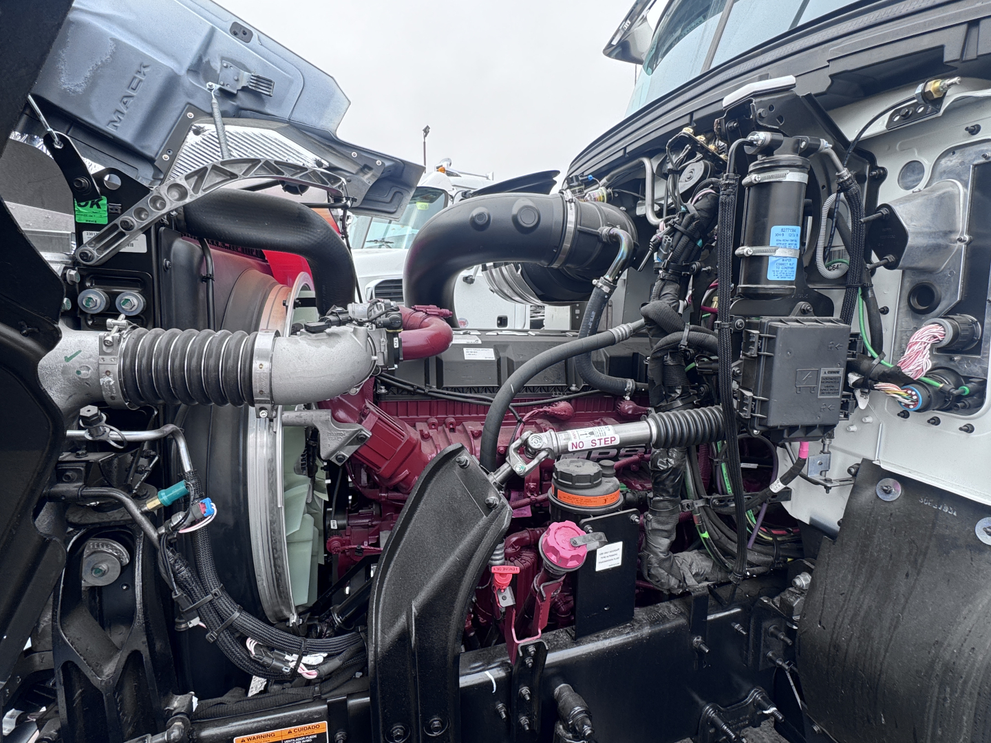 Mack PI64 truck engine bay showing radiator, hoses, turbocharger, and various engine components.