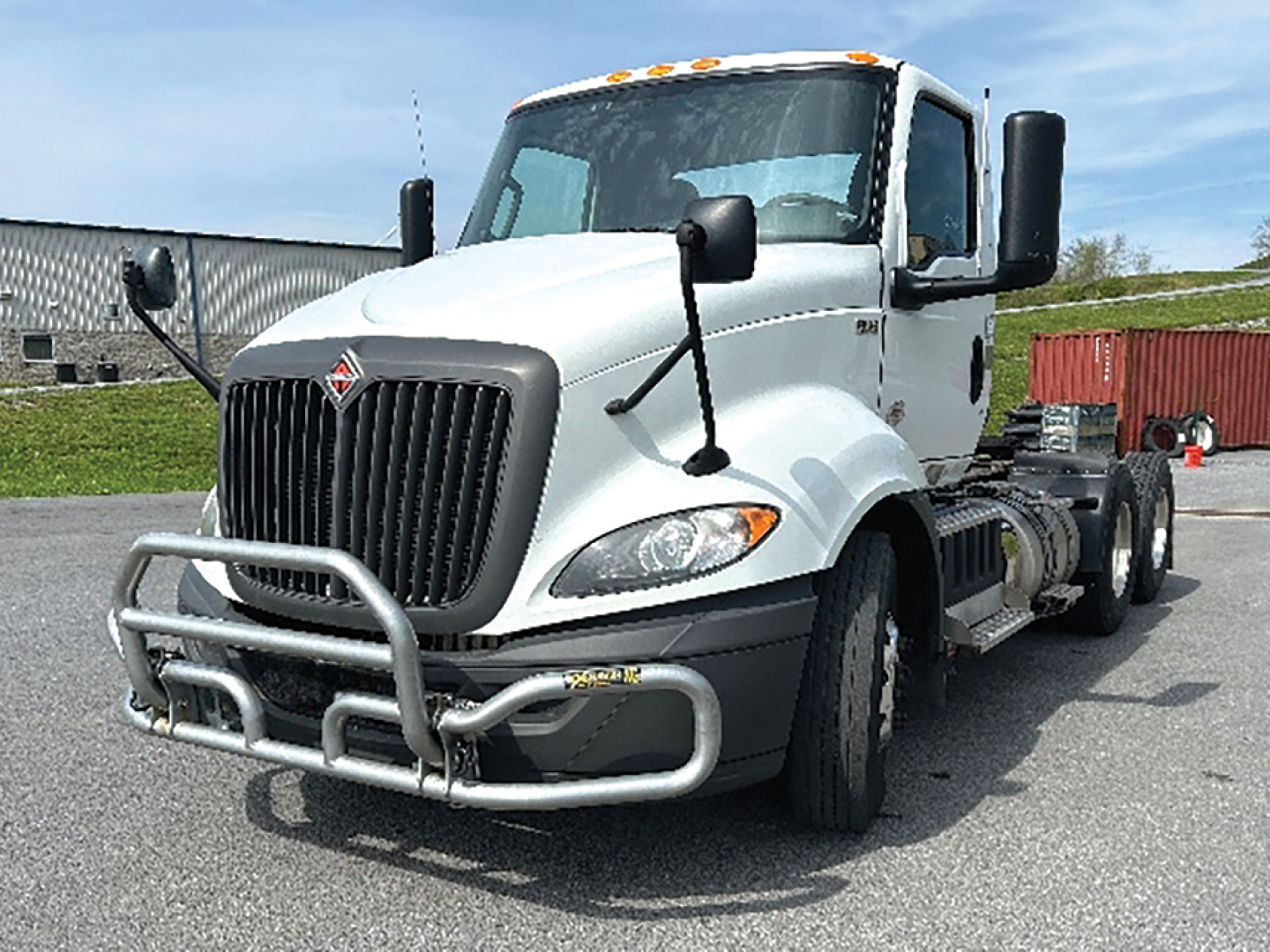 Truck cab and chassis showing front bull bar, International RH613 badge, white exterior, dual side mirrors, and blank rear frame chassis.