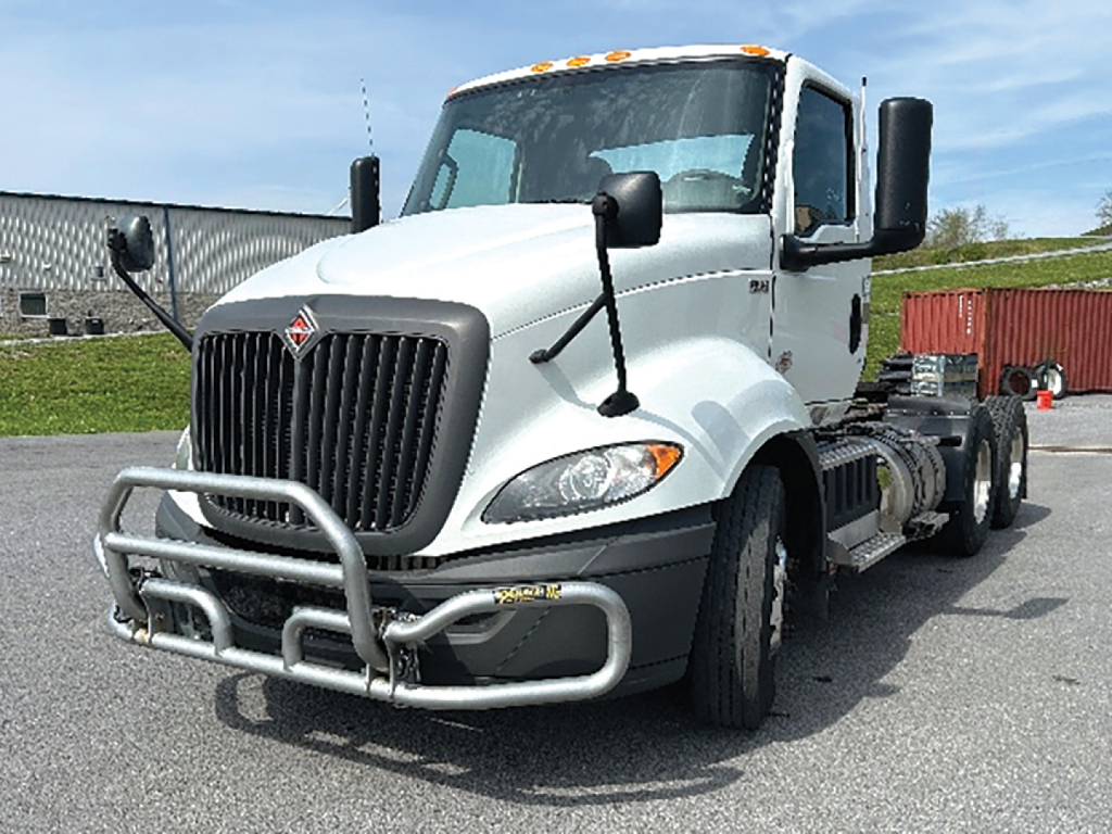 Truck cab and chassis showing front bull bar, International RH613 badge, white exterior, dual side mirrors, and blank rear frame chassis.