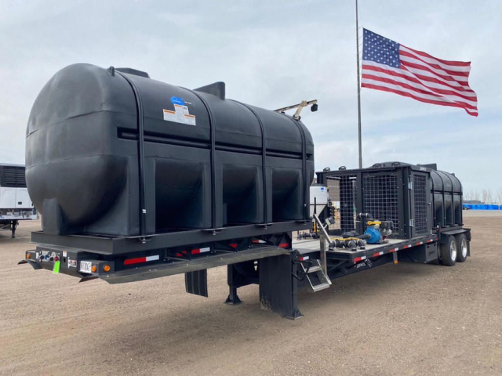 Demco Liquid Tender trailer on a flatbed with twin tank cylinders, American flag in background, VIN tag and stock number not visible clearly.